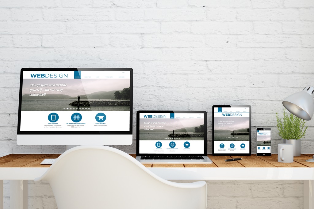 Schreibtisch mit Bildschirm, Tablet und Smartphone, alle zeigen dieselge Website